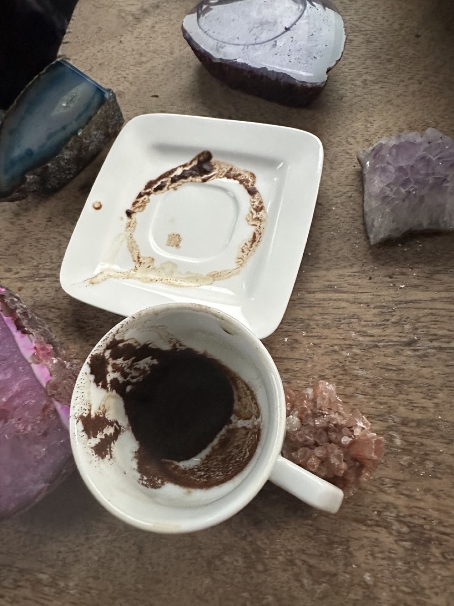 Omgekeerd koffiekopje met een koffiedik-patroon op het schoteltje, tussen edelstenen