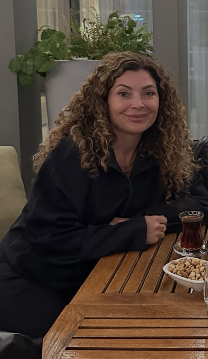 Asuman lachend aan tafel met een glas Turkse thee